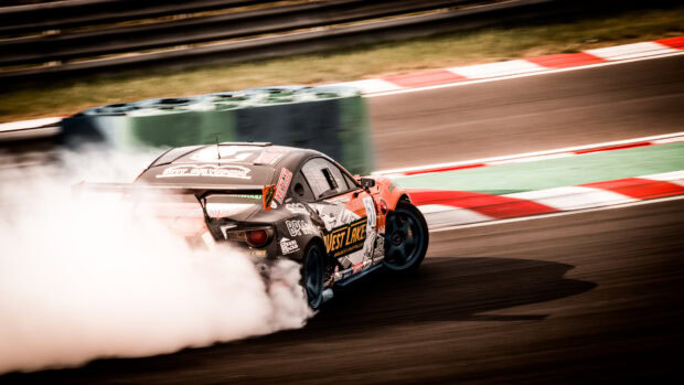 A drifting car with tire smoke on a racing track during a high speed turn