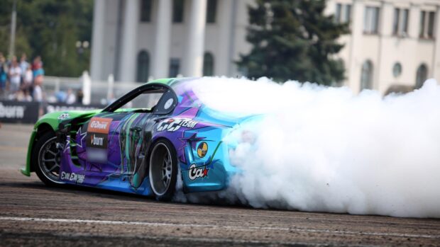 A colorful drifting car creating thick smoke while sliding on the track