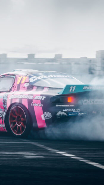 A car performing drifting with pink stripes creating smoke on a racing track