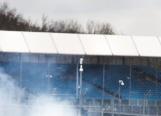 A drifting car performing a sharp turn on a race track with tire smoke around