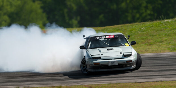 A drifting car producing smoke on a racing track in a drifting event