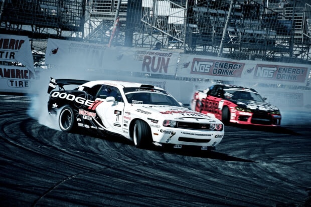 Two drift cars sliding on the race track creating smoke and tire marks