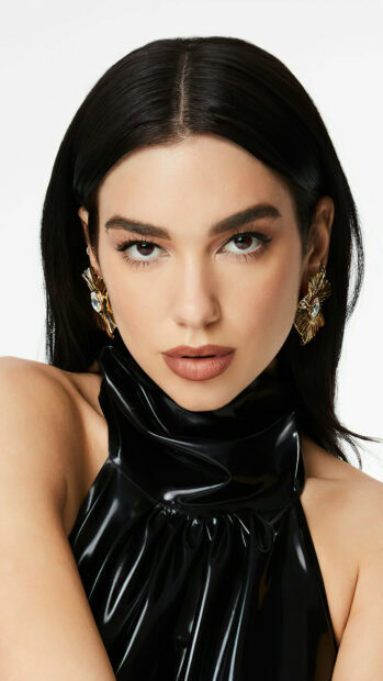 Close up of Dua Lipa with dark hair and golden earrings