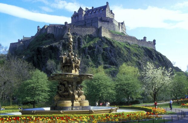 Edinburgh Castle surrounded by greenery and a decorative fountain in a vibrant garden
