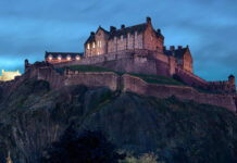 Edinburgh Castle stands majestically on a rocky hill during twilight with illuminated windows