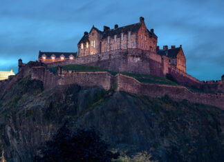 Edinburgh Castle stands majestically on a rocky hill during twilight with illuminated windows