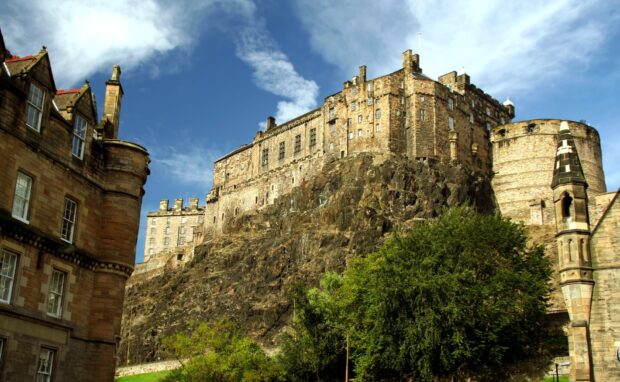 Edinburgh Castle sitting atop a rocky hill surrounded by historic buildings and greenery