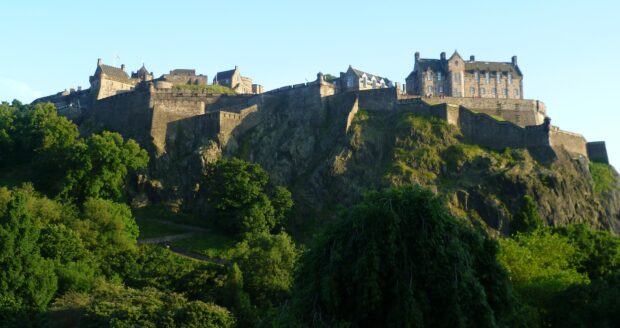 Edinburgh Castle stands majestically on a rocky hill surrounded by lush green trees