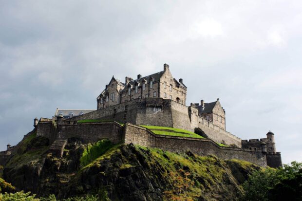 Edinburgh Castle stands prominently on a rocky hill surrounded by greenery