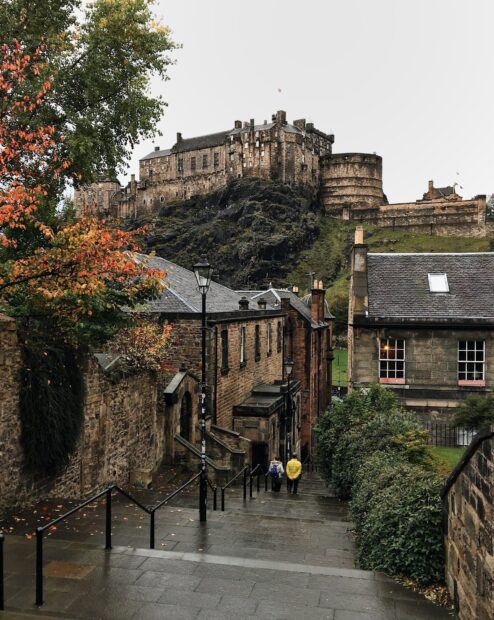 Historic Edinburgh Castle and surrounding buildings viewed from a street during autumn