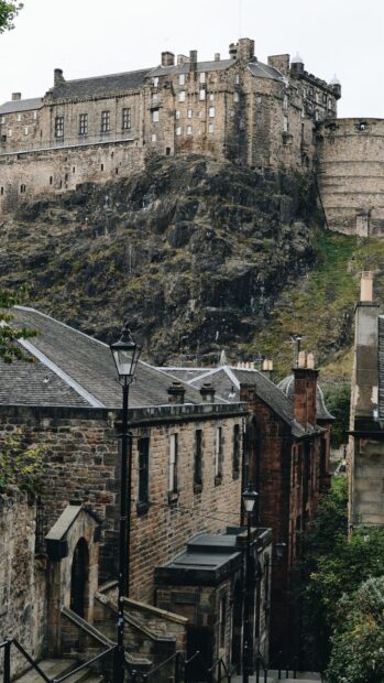Historic Edinburgh Castle on rocky hill overlooking old stone buildings in the city