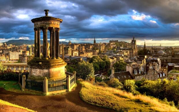 The Dugald Stewart monument overlooking Edinburgh Scotland cityscape under dramatic clouds