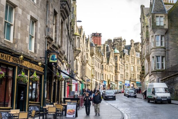 A busy street scene in Edinburgh Scotland with historic buildings and pedestrians walking