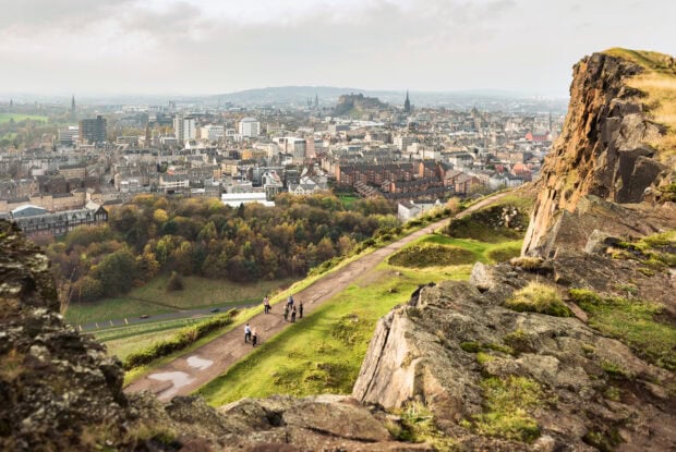 Hikers walking along a trail with Edinburgh Scotland cityscape in the background