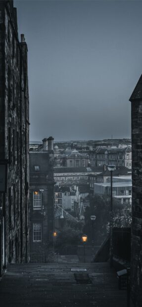 Narrow street view of Edinburgh Scotland with old buildings and street lamps at dusk