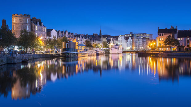 Historic Edinburgh Scotland cityscape reflecting on calm water at twilight