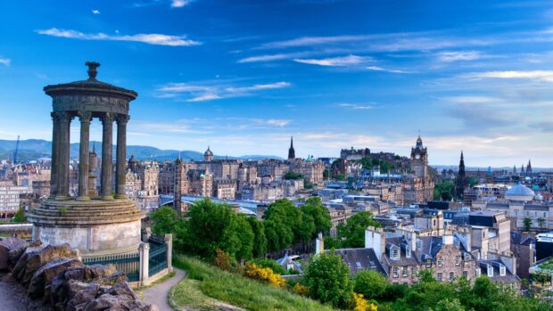 Ancient Dugald Stewart monument overlooking Edinburgh Scotland cityscape under blue sky