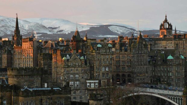 Historic Edinburgh Scotland cityscape with snow covered hills in the background