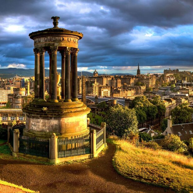 Dugald Stewart monument overlooking Edinburgh Scotland cityscape under dramatic sky