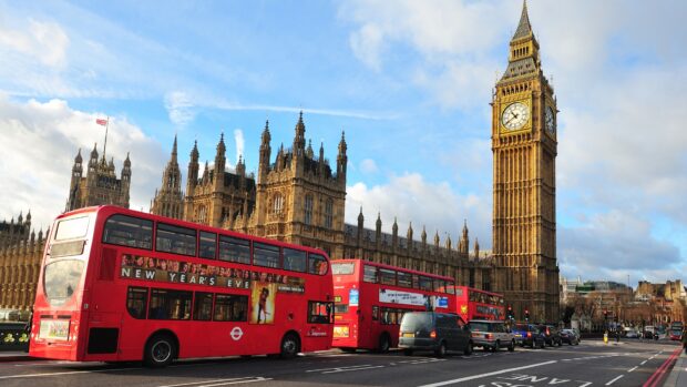 A busy London street scene with iconic England buses and the Big Ben clock tower in the background