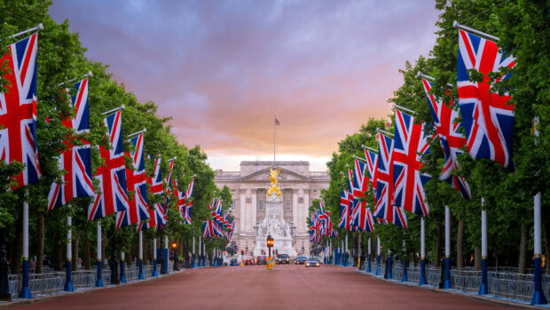 The scene of England with Union flags lining the street leading to a royal building at sunset