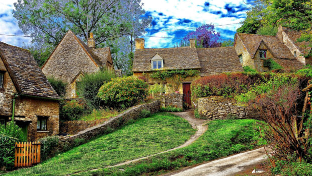 Traditional England stone cottages surrounded by greenery and blue sky