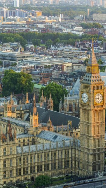 Historic clock tower and buildings in England cityscape with greenery in background