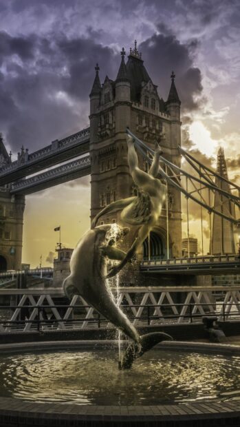 The Tower of London with a dolphin and girl statue fountain at sunset in England