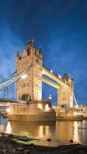 Tower Bridge is a famous landmark in England illuminated at night reflecting on the river