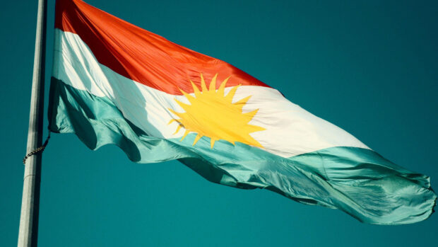 Kurdish flag waving under clear blue sky