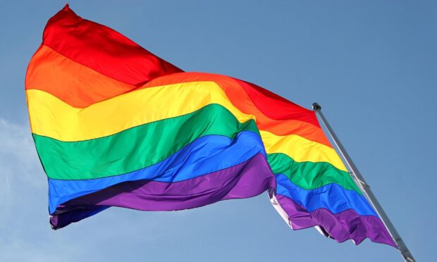 Rainbow pride flag waving in the sky symbolizing diversity and inclusion