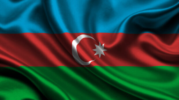 The Azerbaijan flag waving in the wind showing blue red and green stripes with a crescent and star