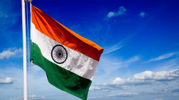 Indian flag waving against a blue sky with clouds