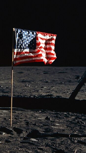 The american flag standing on the moon surface in a dark space setting
