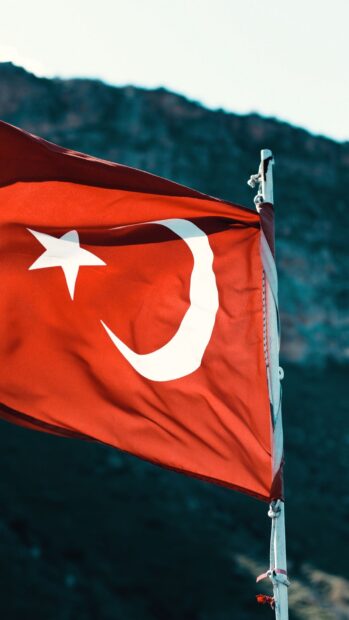 Turkish flag waving in the wind against a mountain background