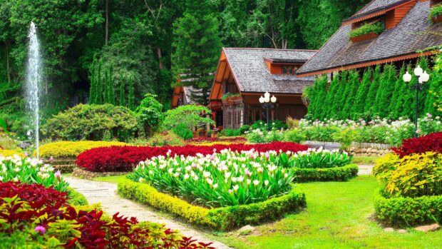 A vibrant flower garden with colorful plants and traditional wooden houses surrounded by lush greenery