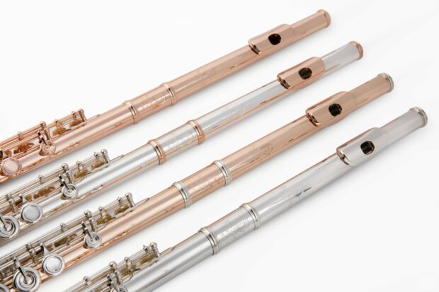 Three metal flutes arranged side by side with silver and rose gold finishes on a white background