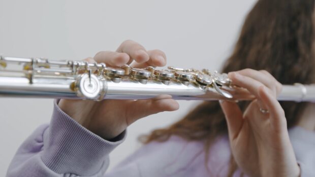 Close up of hands playing flute with detailed keys and fingers on the instrument