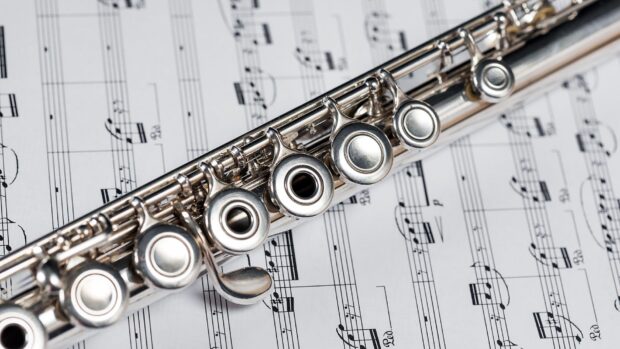 Close up of flute keys placed on a music sheet with clear musical notes