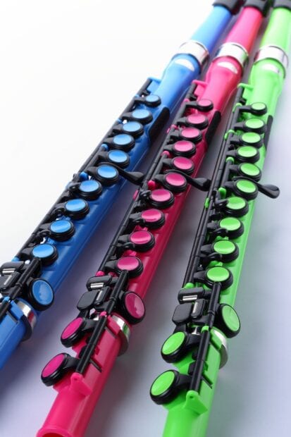 Colorful flute keys on blue pink and green flutes arranged closely together on a white surface
