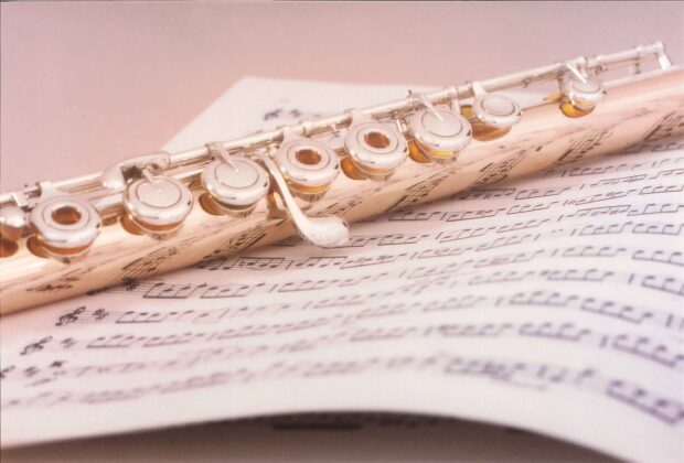 A close up of flute keys resting on music sheets