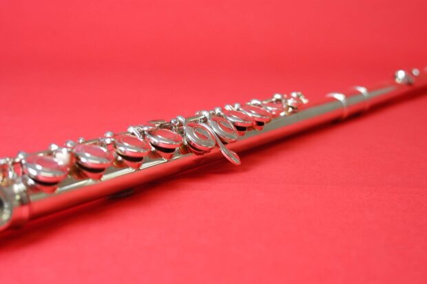 A close up view of a flute showcasing its keys against a red background