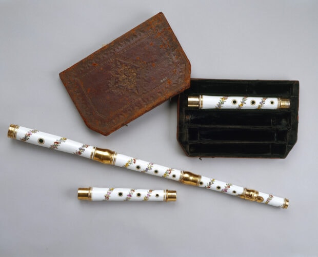 Antique flute with floral design and case on gray surface