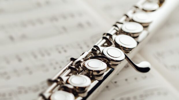 Close up view of a flute placed on music sheets showing its keys and details