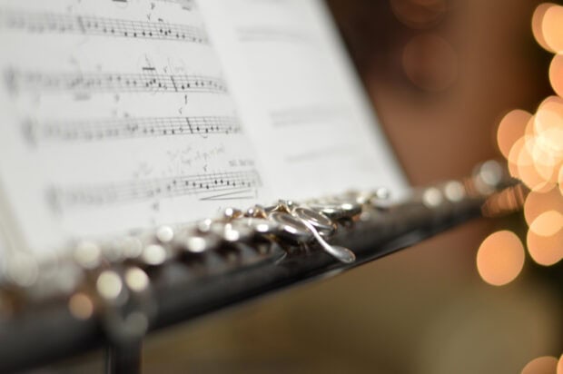 A close up view of flute and music notes on a stand with blurred lights in the background