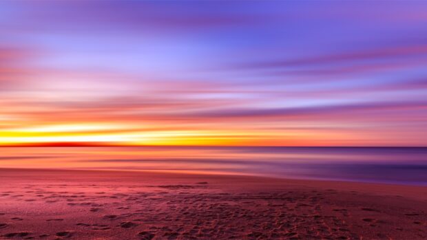 Footprints in the sand along the beach at colorful sunset