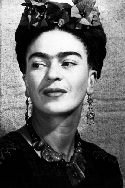Frida Kahlo wearing traditional jewelry and floral headpiece looking to the side