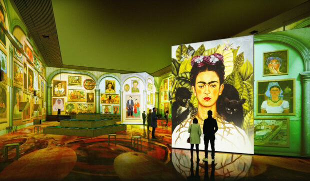 A museum gallery showcasing Frida Kahlo art with visitors admiring the paintings on display