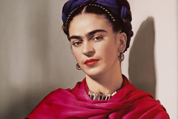 Frida Kahlo wearing a red shawl and distinctive jewelry in a classic portrait style