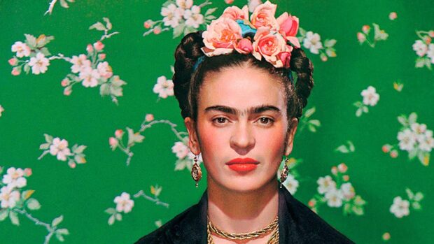 Frida Kahlo with floral headpiece and earrings against a green floral background
